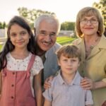 Grandparents in eyeglasses standing by their two cute grandchildren