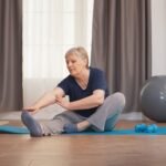 Old woman stretching on yoga mat