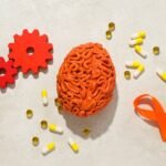Orange human brain model with pills and gears