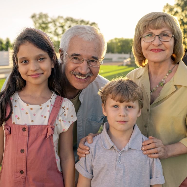 Grandparents in eyeglasses standing by their two cute grandchildren