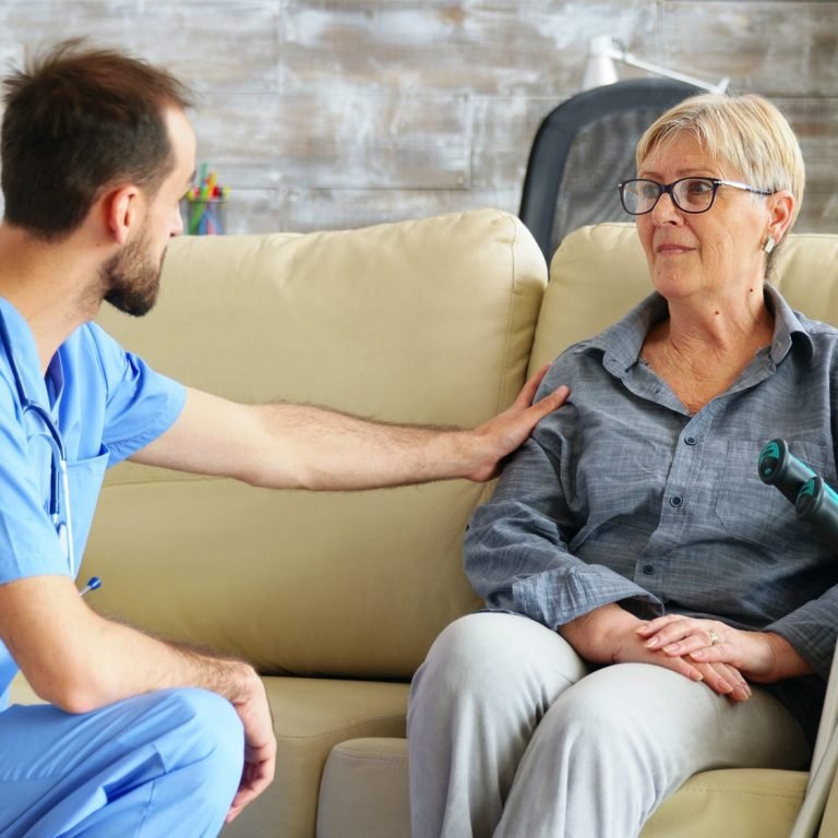 Male nurse talking with old woman suffering of parkinson