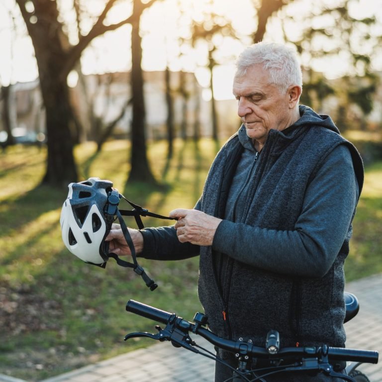 Older Man Holding Helmet on Bike