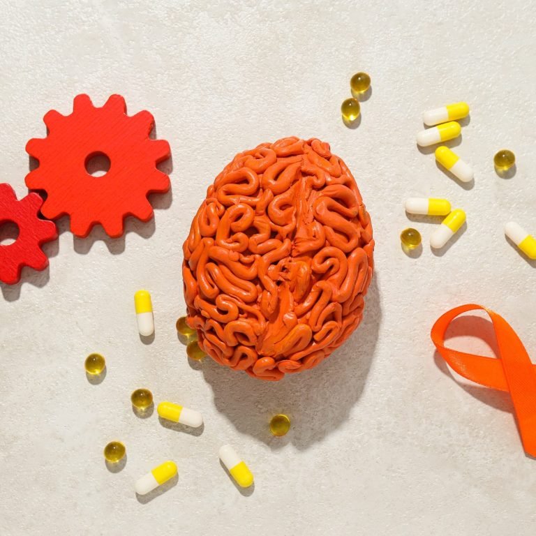 Orange human brain model with pills and gears