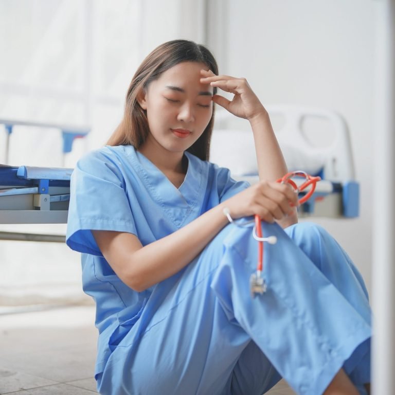Young doctor experiencing burnout sitting on hospital floor